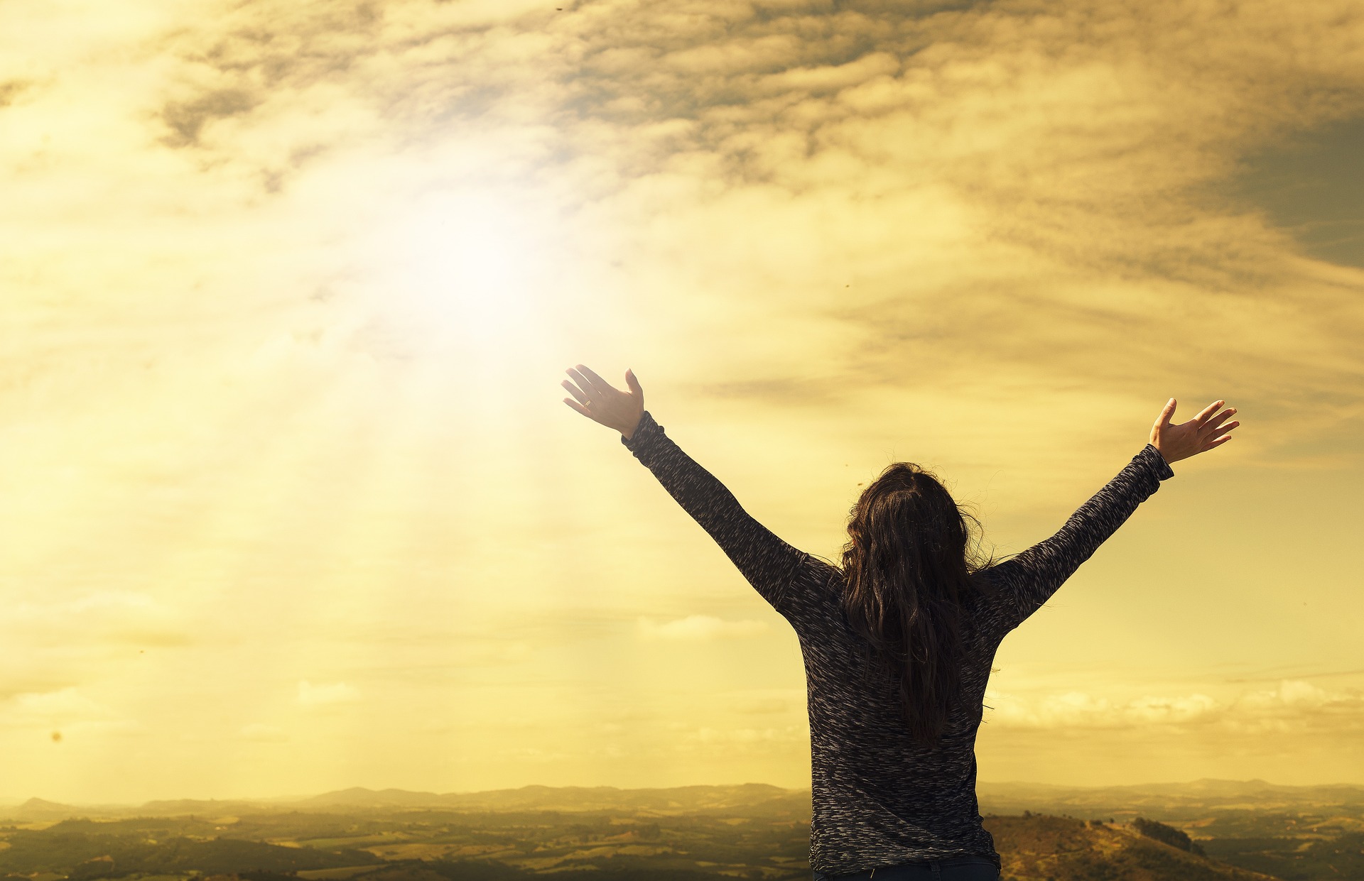 sunrise with person with arms raised silhouetted 